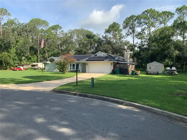 a view of a house with a big yard and large trees
