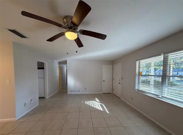 a view of an empty room with window and chandelier fan