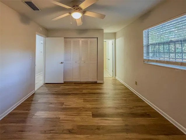 a view of an empty room with wooden floor and a window
