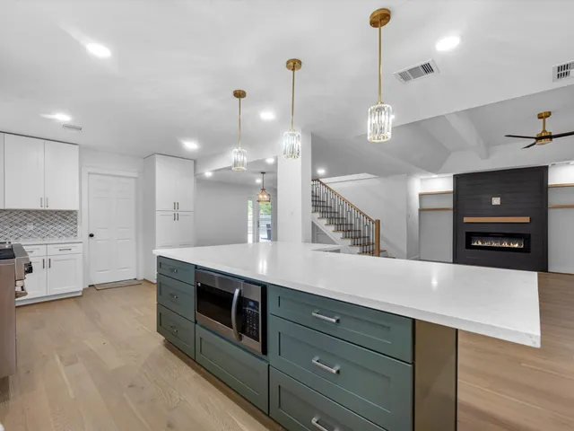 a view of an empty room with wooden floor and a ceiling fan