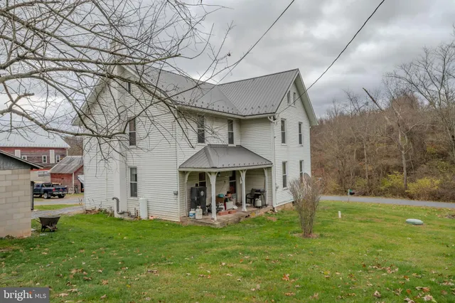 a view of house and yard with trees in the background