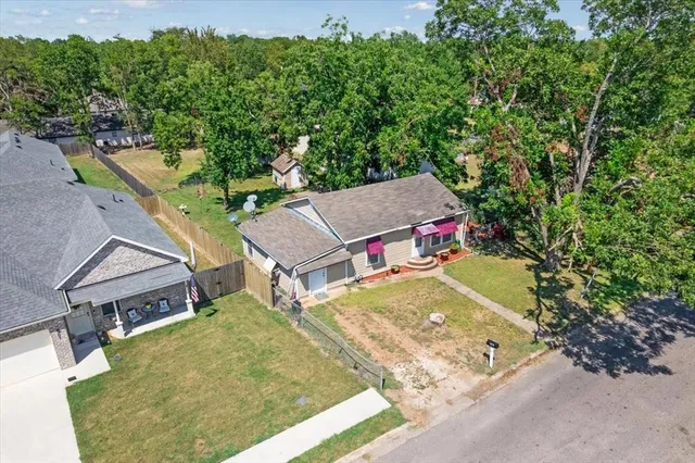 an aerial view of a house with swimming pool and large trees