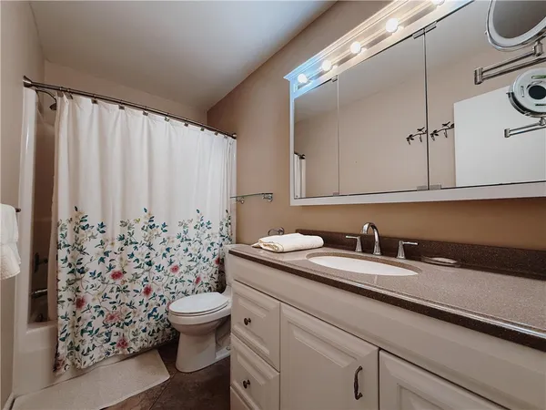 a bathroom with a granite countertop sink and a toilet