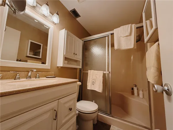a bathroom with a granite countertop toilet sink and mirror