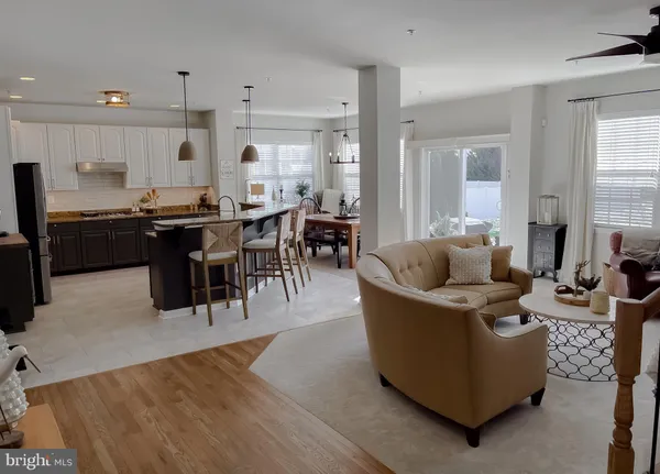 a living room with furniture a wooden floor and kitchen view