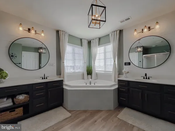 a bathroom with a double vanity sink mirror and bathtub