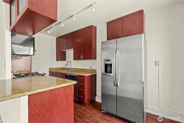 a kitchen with stainless steel appliances granite countertop a refrigerator a sink and wooden cabinets