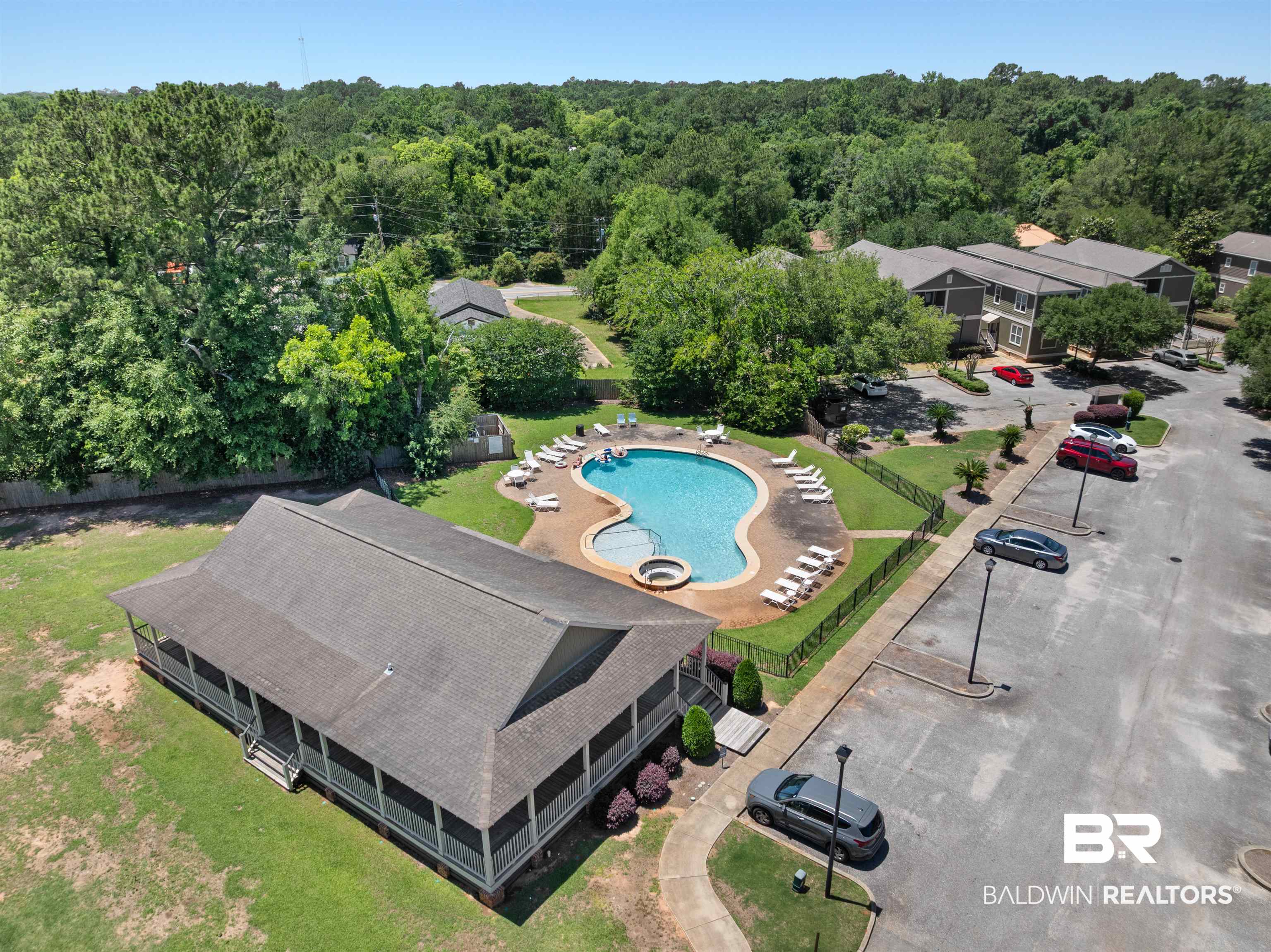 25806 Pollard Road, Unit 6 Daphne, AL 36526 - Photo 32 of 38 Community amenities featuring a freeform swimming pool with a sun shelf and integrated spa, surrounded by lounge seating and a black metal fence