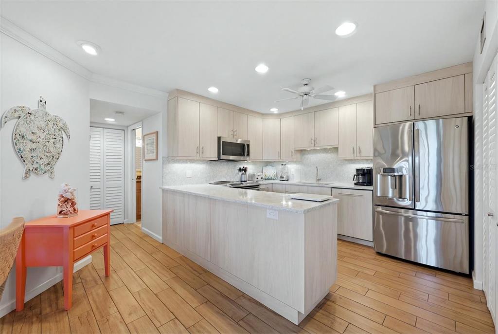 2729 North Beach Road, Unit 211 Englewood, FL 34223 - Photo 18 of 51 a kitchen with stainless steel appliances granite countertop a refrigerator a sink dishwasher a stove with wooden cabinets and floor