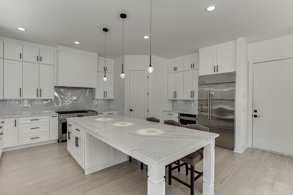 751 Rock Springs Road, Unit 2 Lawrenceville, GA 30043 - Photo 18 of 76 a kitchen with a stove a sink a refrigerator and white cabinets with wooden floor