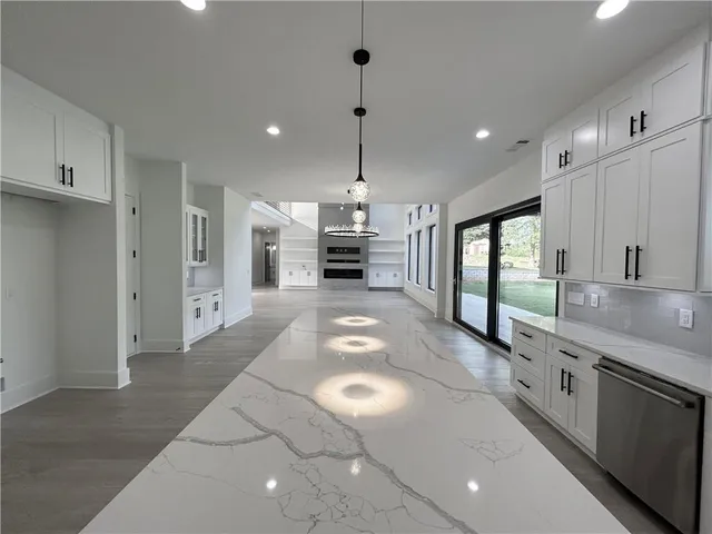 a living room with stainless steel appliances furniture a kitchen view and wooden floor