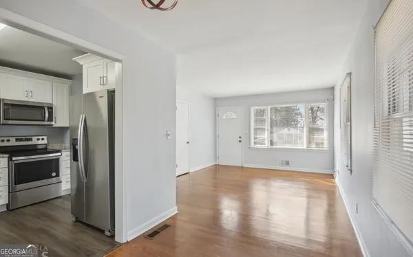 a view of an empty room with a window and wooden floor