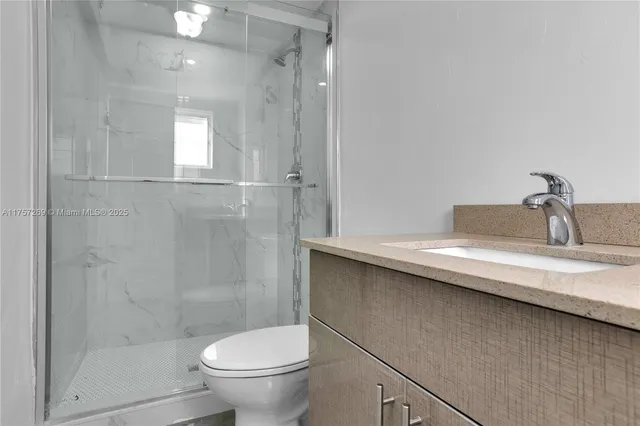 a bathroom with a granite countertop sink a toilet and shower