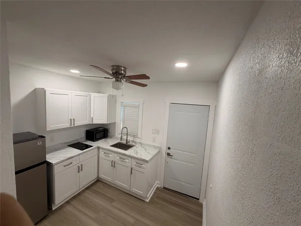 a view of a kitchen with sink microwave and cabinets