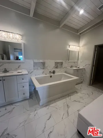 a bathroom with a tub sink and mirror