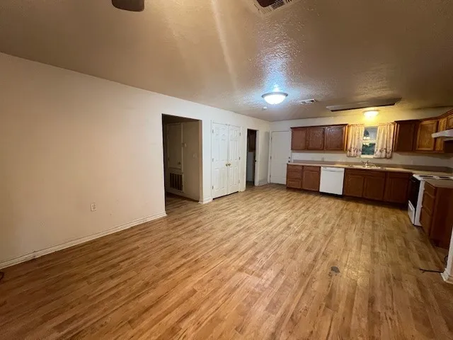 a large white kitchen with wooden floors and stainless steel appliances