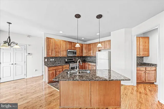 a kitchen with stainless steel appliances granite countertop a sink a stove and a wooden floors