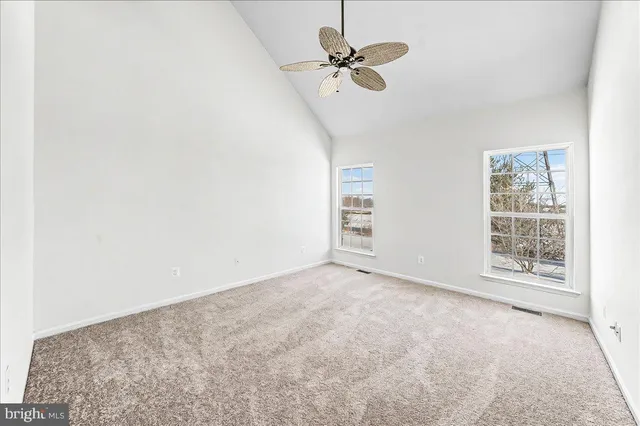 an empty room with windows and fan