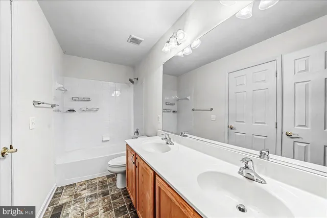 a spacious bathroom with a sink a toilet a shower and a mirror