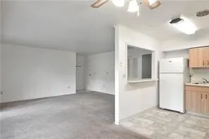 an empty room with a kitchen and a refrigerator