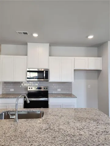 a kitchen with stainless steel appliances granite countertop a sink dishwasher a stove and a refrigerator with wooden floor