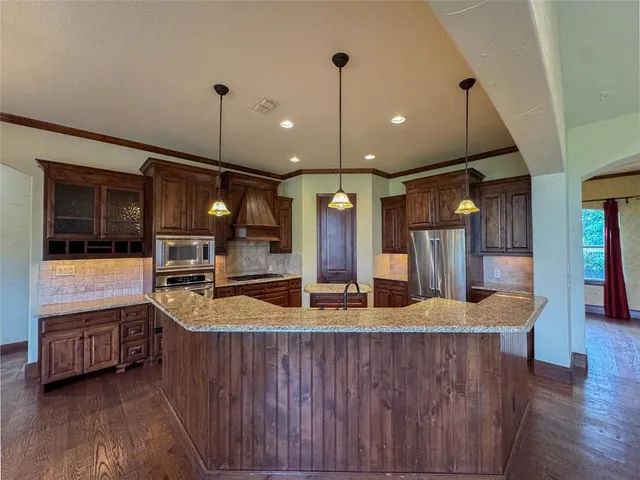 a kitchen with stainless steel appliances granite countertop a sink a oven and a wooden cabinets
