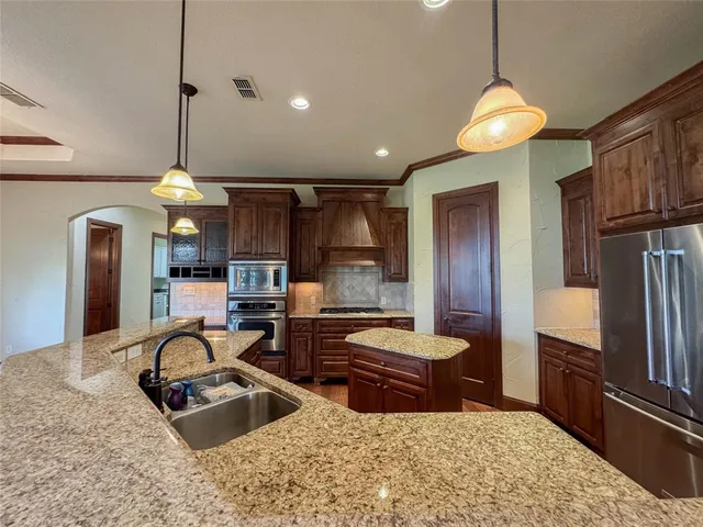 a kitchen with stainless steel appliances granite countertop a sink refrigerator and cabinets