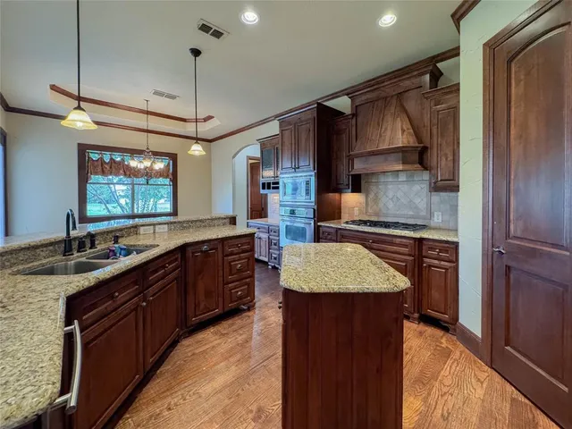 a kitchen with kitchen island granite countertop a sink refrigerator and cabinets