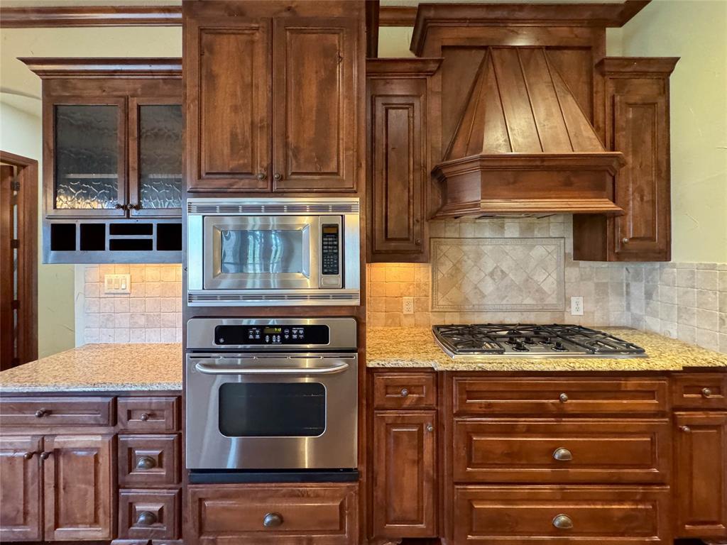 1559 East Blackjack Road East Pilot Point, TX 76258 - Photo 24 of 40 a kitchen with granite countertop a stove and a wooden cabinets