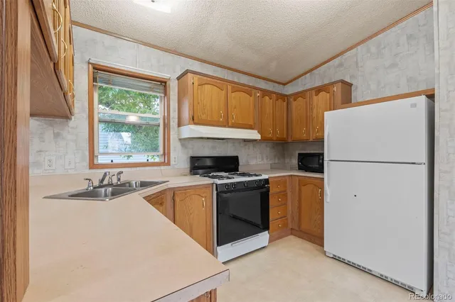 a kitchen with granite countertop a refrigerator stove top oven and sink