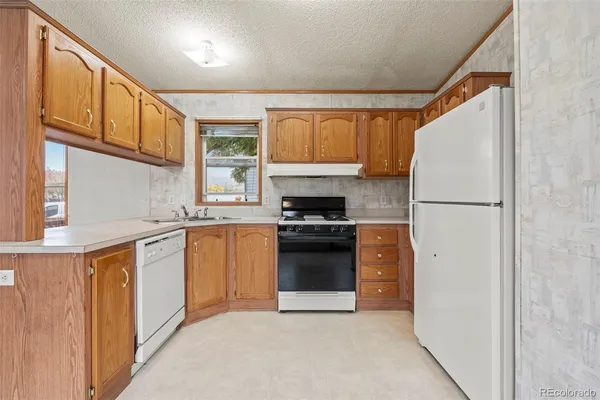 a kitchen with stainless steel appliances granite countertop a refrigerator a stove a sink dishwasher and a refrigerator with wooden cabinets