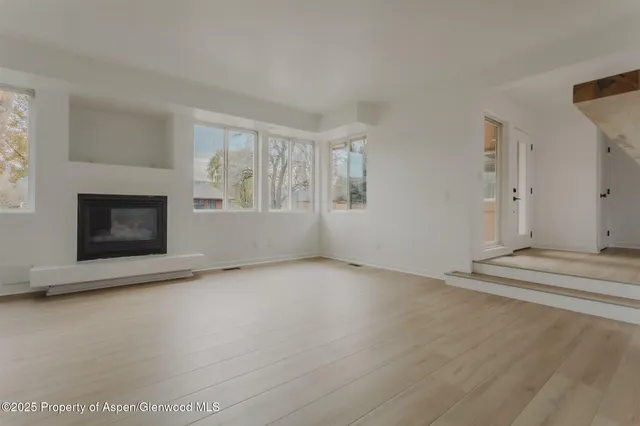 an empty room with windows and fireplace