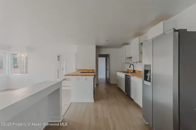a kitchen with a refrigerator a sink and dishwasher with wooden floor