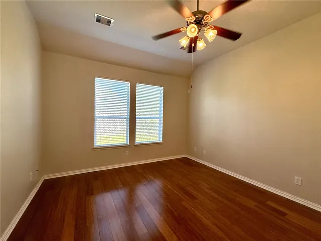 a view of an empty room with window and wooden floor