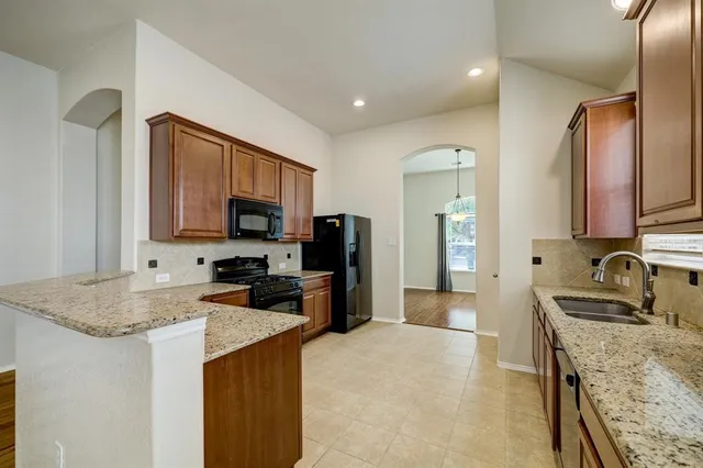 a kitchen with granite countertop a sink and a stove top oven with wooden floor