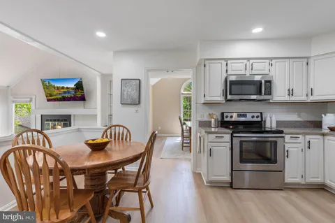 a kitchen with stainless steel appliances granite countertop a refrigerator a stove a sink dishwasher and white cabinets with wooden floor