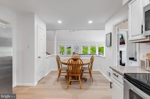 a kitchen with stainless steel appliances a stove a microwave a dining table and chairs