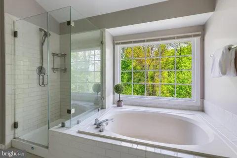 a bathroom with a granite countertop tub sink shower and mirror