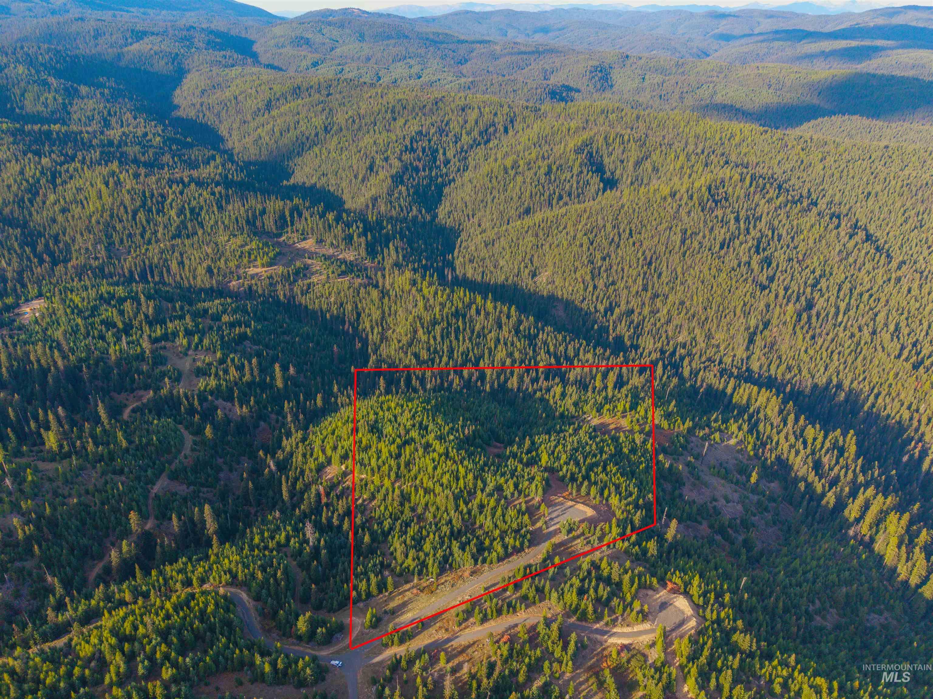 Aerial view of property and surrounding area with a mountain backdrop and property parcel outlined