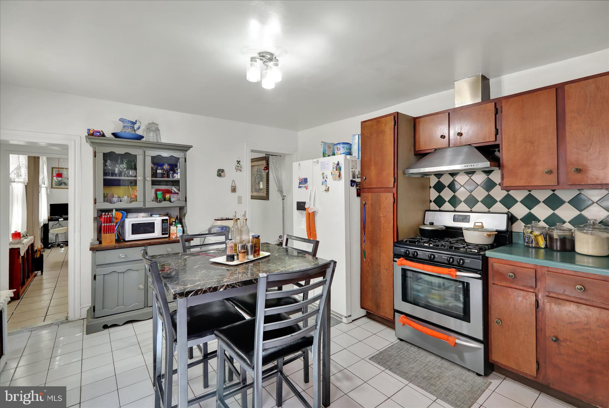 407 South 7th Street Reading, PA 19602 - Photo 15 of 36 a kitchen with stainless steel appliances kitchen island granite countertop a table chairs stove and cabinets