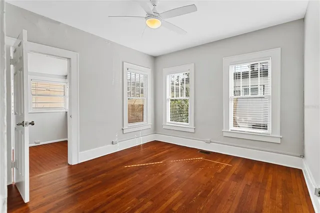 a view of an empty room with window and wooden floor