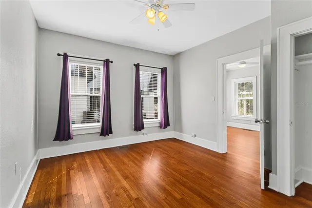 a view of empty room with wooden floor and fan