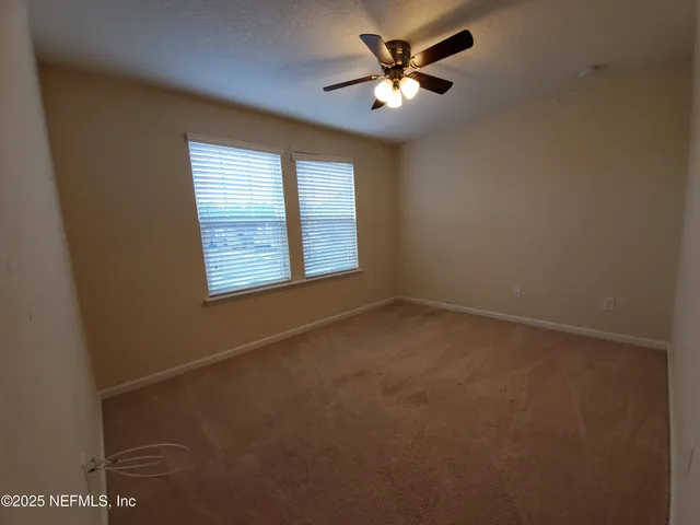 an empty room with windows and fan