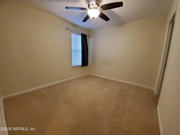 an empty room with a window and a fan