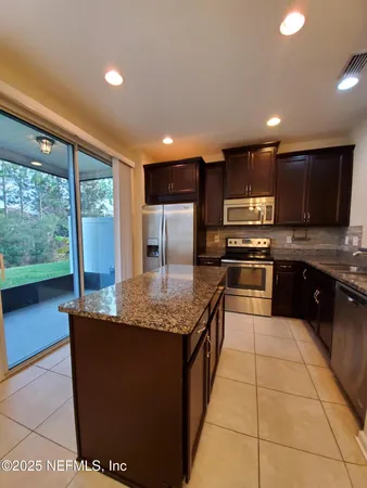 a large kitchen with kitchen island granite countertop a stove a sink and a microwave