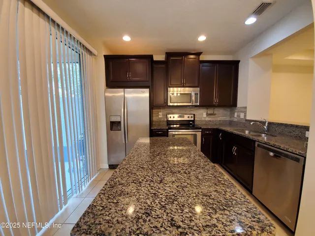 a large kitchen with stainless steel appliances granite countertop a refrigerator and a sink