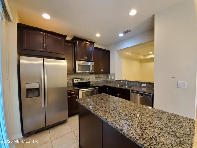 a kitchen with stainless steel appliances granite countertop a refrigerator a sink a stove a microwave and island