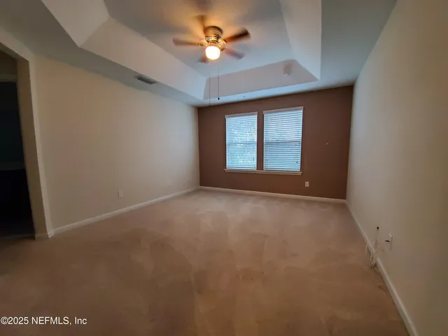 an empty room with a window and a ceiling fan