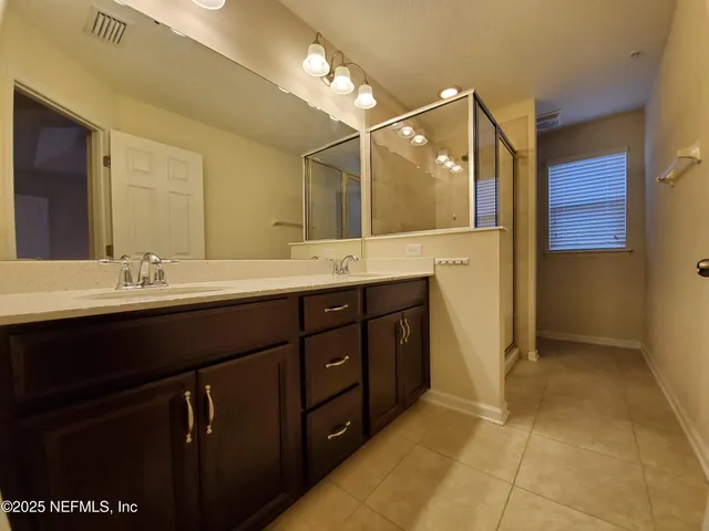 a bathroom with a double vanity sink a mirror and shower