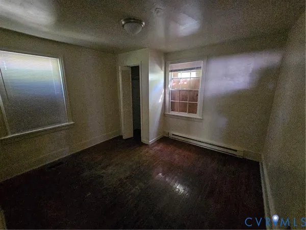 an empty room with wooden floor and windows